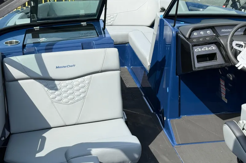 Slide: The Image of 2026 MasterCraft NXT24 boat interior with blue and gray seating and dashboard. - 6