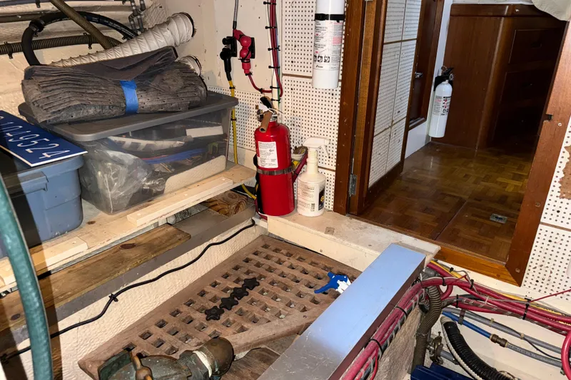 Slide: The Image of Engine room of 1991 Grand Banks 42 Classic with fire extinguishers and storage containers. - 117