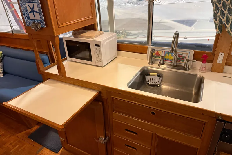 Slide: The Image of 1991 Grand Banks 42 Classic kitchen with sink, microwave, and wooden cabinetry. - 25
