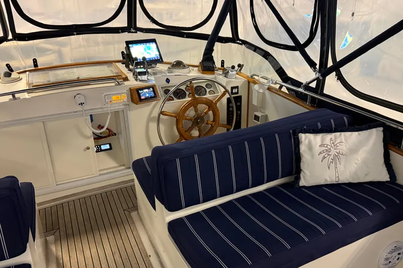 Slide: The Image of 1991 Grand Banks 42 Classic yacht interior with helm, wooden wheel, and blue-striped seating. - 79