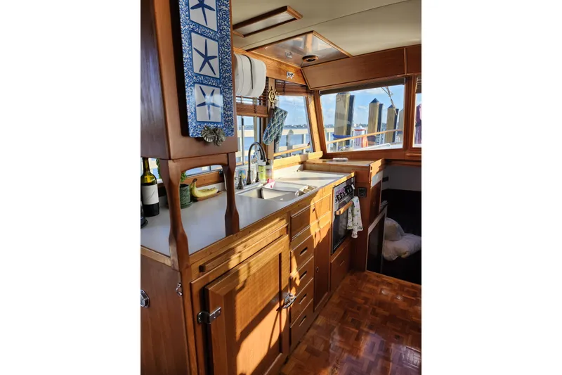 Slide: The Image of Interior of 1991 Grand Banks 42 Classic yacht, featuring a wooden kitchen with nautical decor. - 31