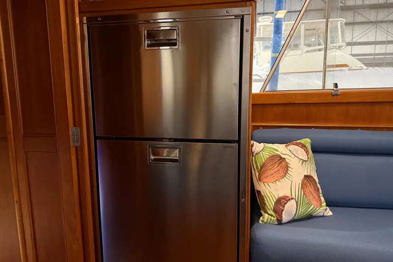 Slide: The Image of Stainless steel fridge in 1991 Grand Banks 42 Classic yacht interior with blue seating and decorative pillow. - 23