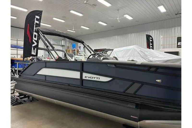 Slide: The Image of 2026 Evotti 521CS pontoon boat displayed indoors with branded flags. - 11