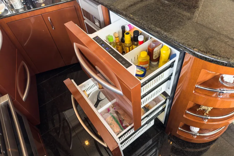 Slide: The Image of Luxury yacht kitchen with open drawers, showcasing organized condiments and sleek cabinetry in a 2005 Marquis Pilothouse. - 35