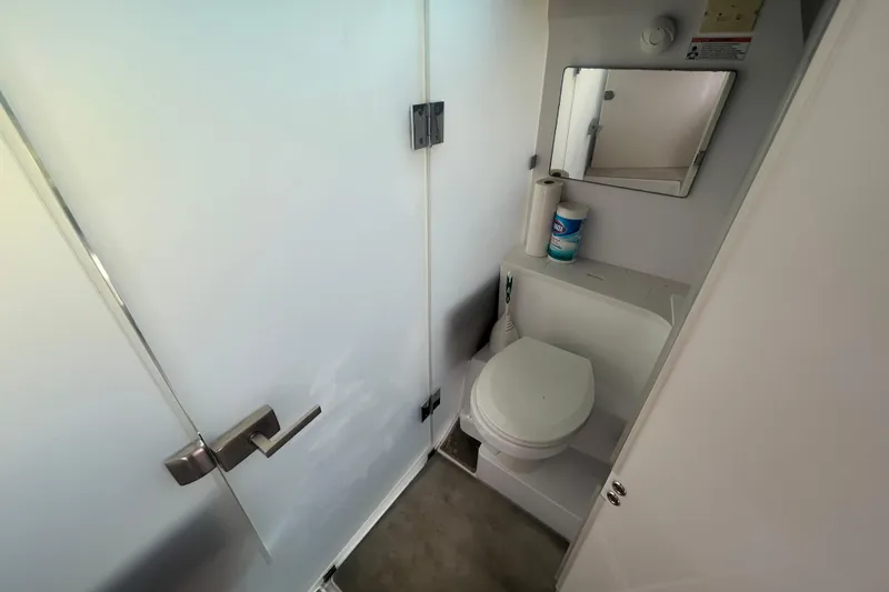 Slide: The Image of 2021 Axopar 37 Sun-Top boat bathroom with toilet, mirror, and cleaning supplies. - 16