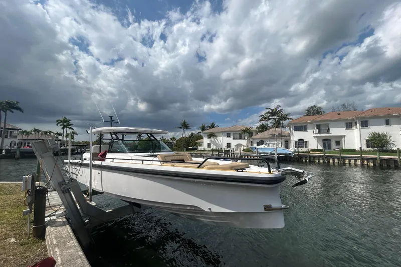 Slide: The Image of 2021 Axopar 37 Sun-Top boat docked by waterfront homes under cloudy sky. - 4