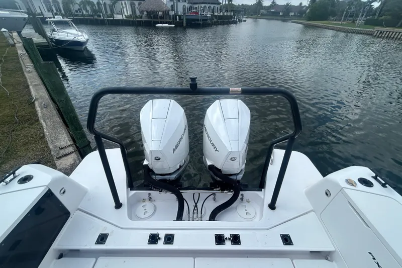 Slide: The Image of 2021 Axopar 37 Sun-Top with twin Mercury outboard engines on a calm waterfront. - 6