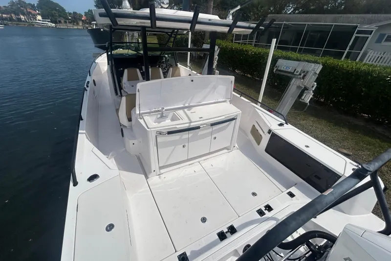 Slide: The Image of 2021 Axopar 37 Sun-Top boat with open deck and seating, docked by the water. - 7