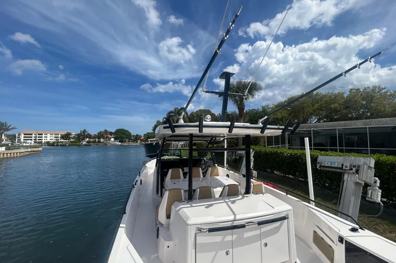 Slide: The Image of 2021 Axopar 37 Sun-Top boat docked by a scenic waterfront under a blue sky. - 8
