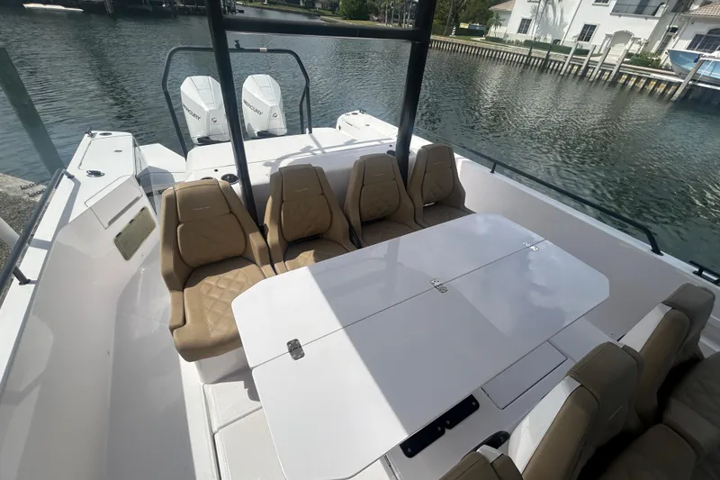 Slide: The Image of 2021 Axopar 37 Sun-Top boat interior with seating and table, docked by the water. - 9