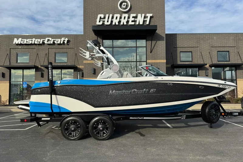 Slide: The Image of 2021 MasterCraft XT22 boat on trailer outside dealership, showcasing sleek design and vibrant colors. - 2