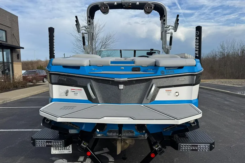 Slide: The Image of 2021 MasterCraft XT22 boat, blue and white, parked outdoors with a clear sky background. - 4