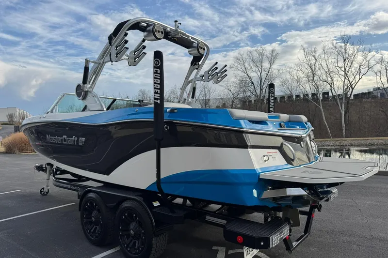Slide: The Image of 2021 MasterCraft XT22 boat on trailer, blue and black design, parked outdoors. - 5