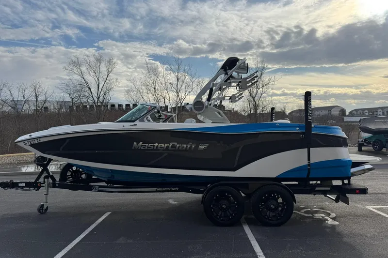Slide: The Image of 2021 MasterCraft XT22 boat on trailer, parked outdoors under cloudy sky. - 6