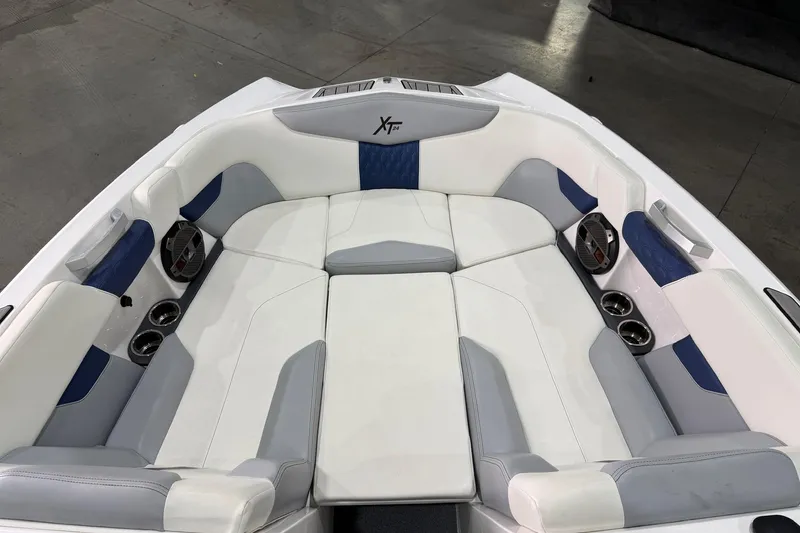 Slide: The Image of 2022 MasterCraft XT24 boat interior with white and blue seating, cup holders, and speakers. - 5