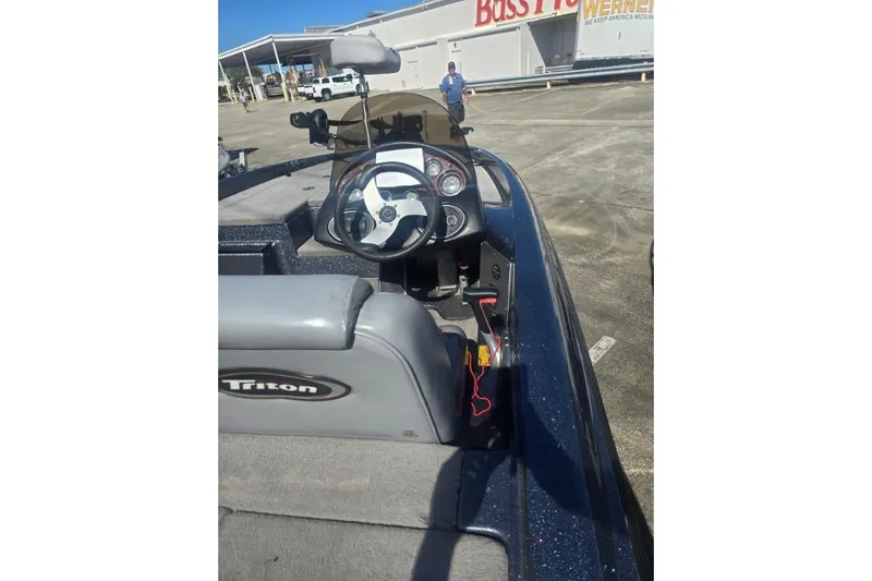 Slide: The Image of 2006 Triton Tr-176 boat interior with steering wheel and dashboard in a parking lot. - 7