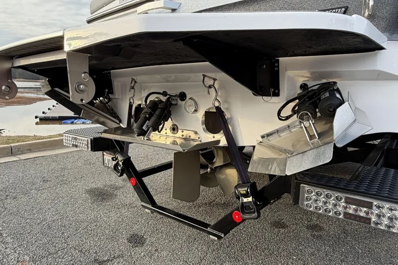 Slide: The Image of 2023 MasterCraft XT24 boat stern with propeller and trim tabs, parked on pavement. - 3
