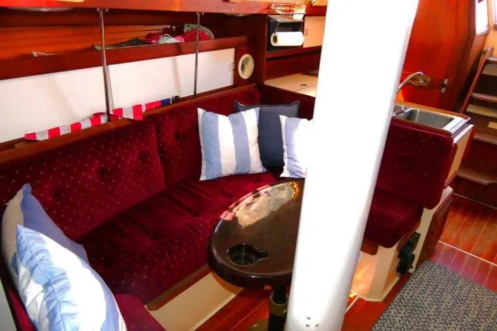 Slide: The Image of Interior of a 1989 Catalina 34 sailboat with red seating and striped pillows. - 11