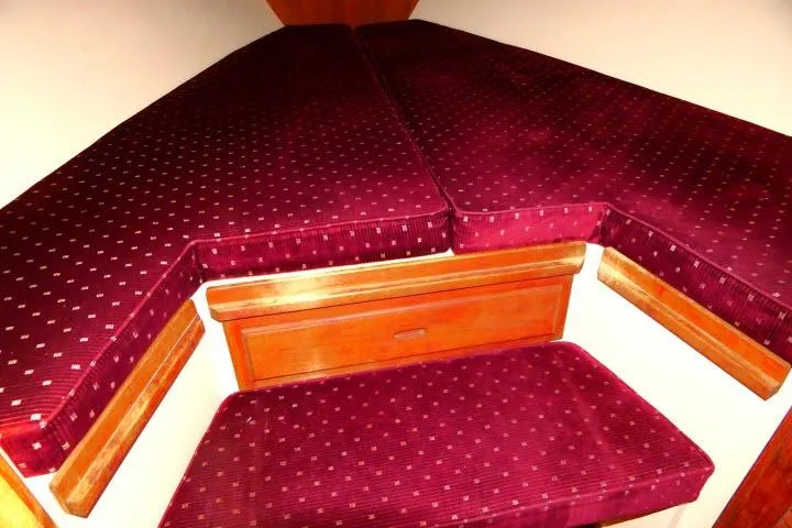 Slide: The Image of 1989 Catalina 34 interior with red cushioned seating and wooden storage. - 21