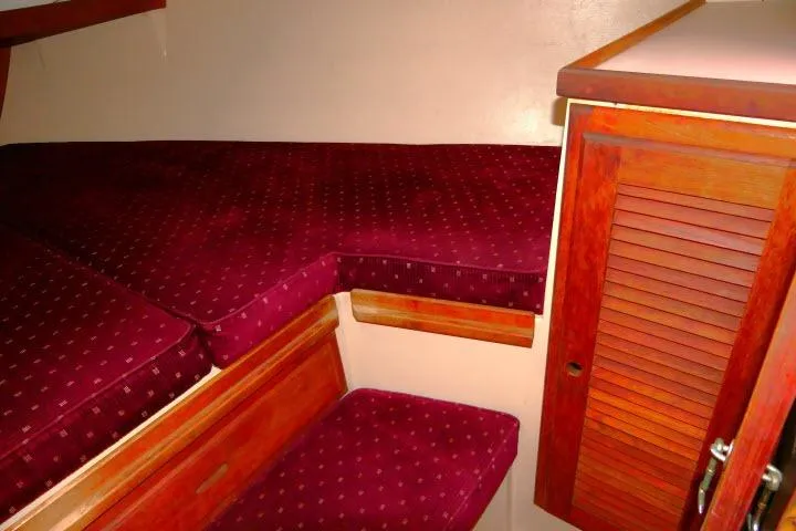 Slide: The Image of 1989 Catalina 34 interior cabin with red cushioned seating and wooden cabinetry. - 24