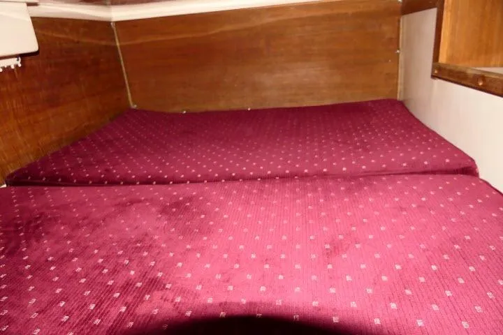 Slide: The Image of 1989 Catalina 34 interior cabin with maroon bedding and wooden paneling. - 29