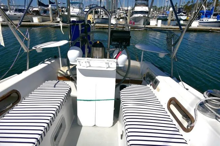 Slide: The Image of 1989 Catalina 34 sailboat cockpit with striped cushions, docked in a marina. - 30