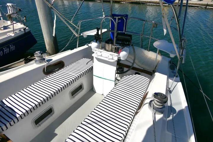 Slide: The Image of 1989 Catalina 34 sailboat cockpit with striped cushions, docked in a marina. - 33