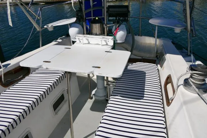 Slide: The Image of Cockpit of 1989 Catalina 34 sailboat with striped seating and foldable table. - 35