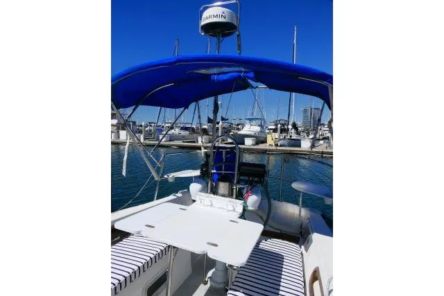 Slide: The Image of 1989 Catalina 34 sailboat with blue canopy docked at marina, featuring striped seating and navigation equipment. - 36
