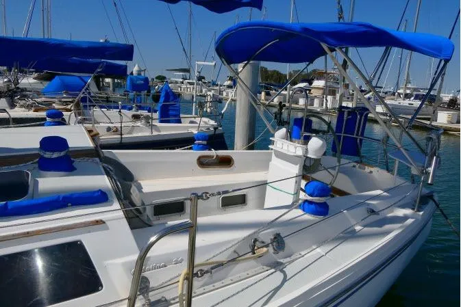 Slide: The Image of 1989 Catalina 34 sailboat docked, featuring blue canvas covers and a spacious cockpit. - 50
