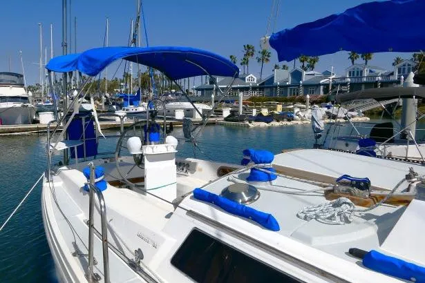 Slide: The Image of 1989 Catalina 34 sailboat docked in a sunny marina with blue canopies. - 51