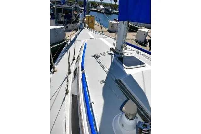 Slide: The Image of 1989 Catalina 34 sailboat deck with blue accents, docked in a marina. - 54
