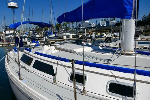 Slide: The Image of 1989 Catalina 34 sailboat docked in marina with blue accents and clear sky. - 61