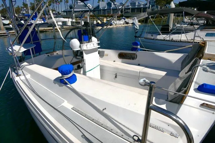 Slide: The Image of 1989 Catalina 34 sailboat cockpit with marina backdrop, featuring clean white seating and blue accents. - 62