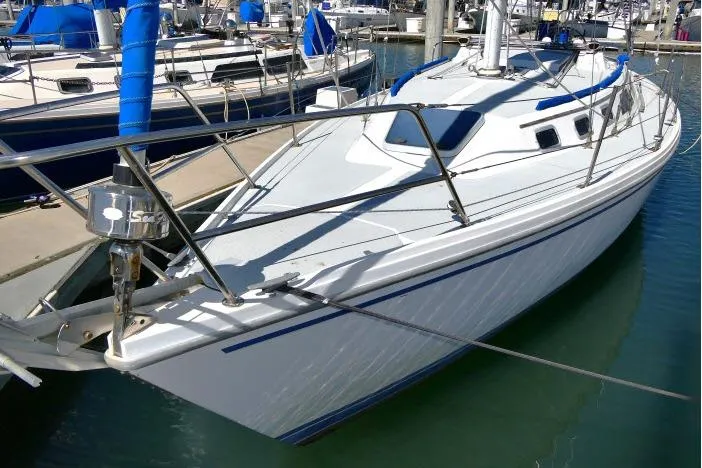 Slide: The Image of 1989 Catalina 34 sailboat docked in marina, featuring sleek white hull and blue accents. - 63