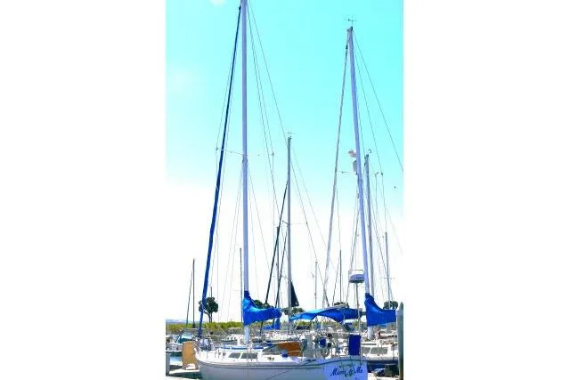 Slide: The Image of 1989 Catalina 34 sailboat docked in a marina with blue sails and clear sky. - 75
