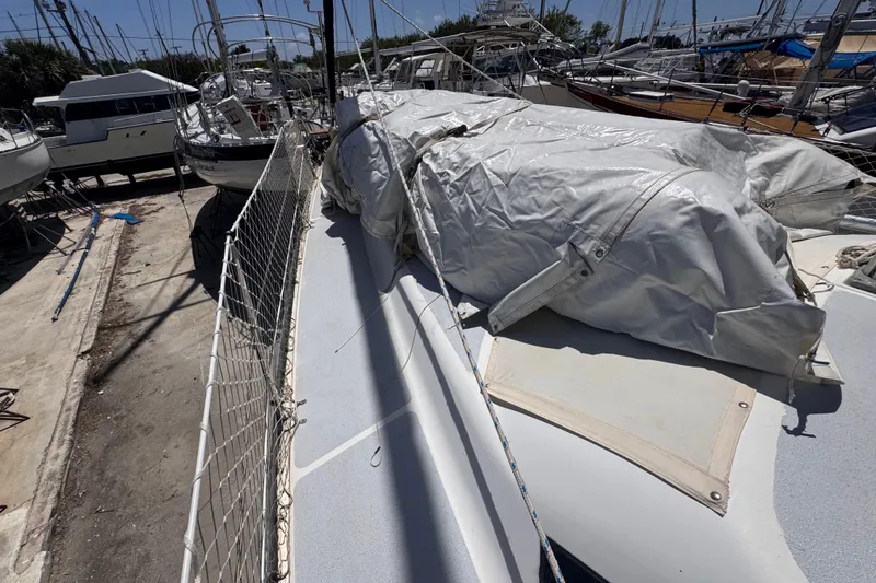 Slide: The Image of 1992 Hunter Passage 42 sailboat on dry dock, covered with tarpaulin, surrounded by other boats. - 35