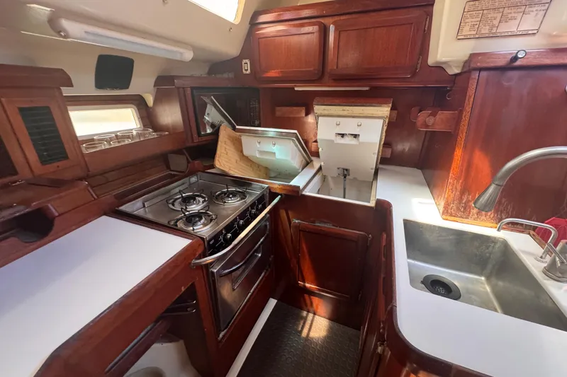 Slide: The Image of 1992 Hunter Passage 42 yacht kitchen with stove, sink, and wooden cabinetry. - 75