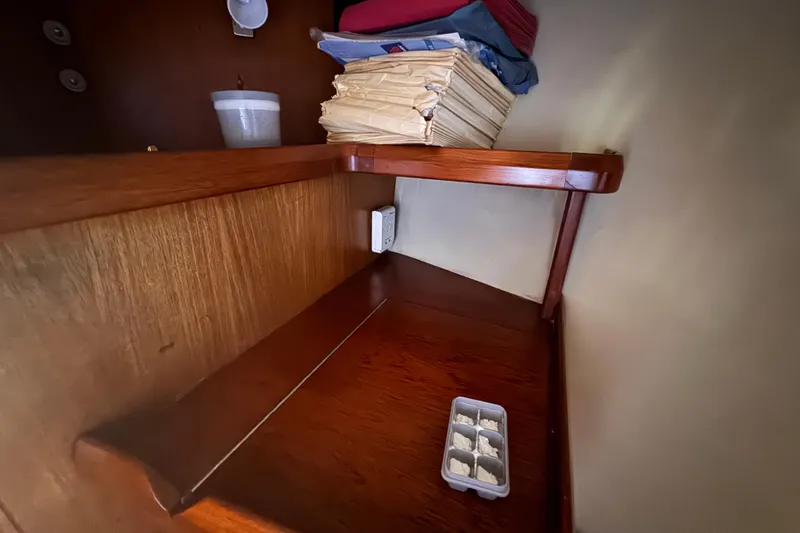 Slide: The Image of Wooden shelf inside a 1992 Hunter Passage 42 yacht with papers and a container. - 95