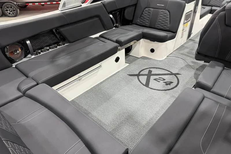 Slide: The Image of 2021 MasterCraft X24 boat interior with luxurious black seating and logo on carpet. - 12
