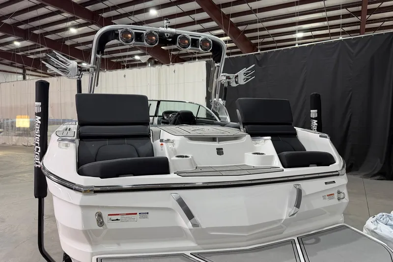 Slide: The Image of 2021 MasterCraft X24 boat interior with black seating and chrome accents in a showroom. - 7