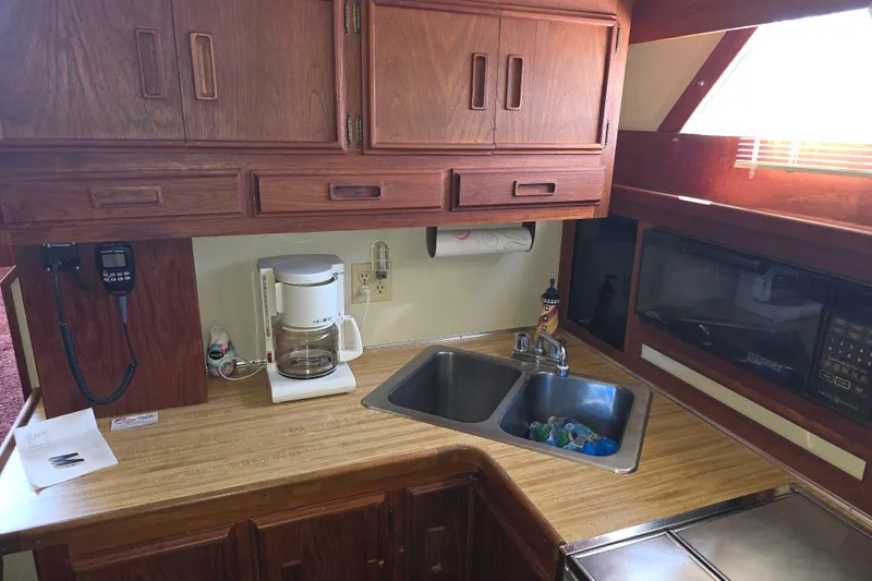 Slide: The Image of 1988 Marinette 37 Motor Yacht kitchen with wooden cabinets, sink, coffee maker, and microwave. - 48