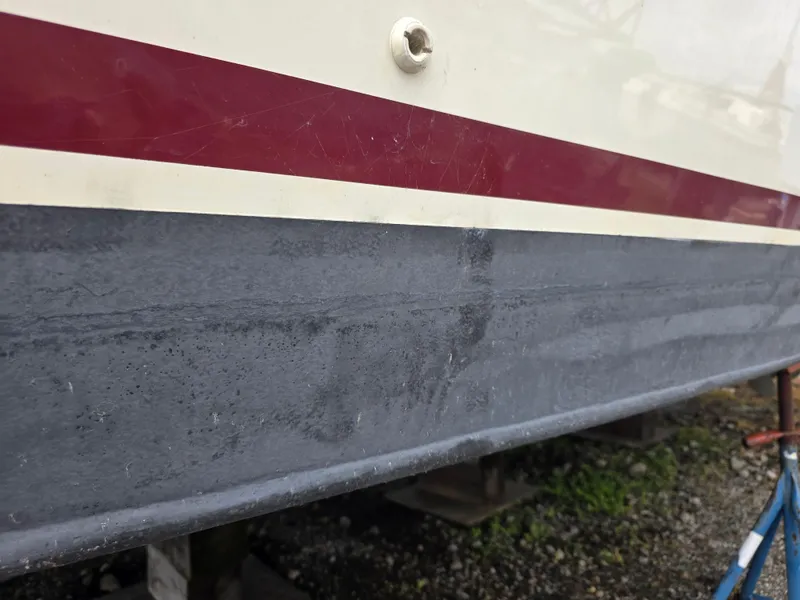 Slide: The Image of 1988 Marinette 37 Motor Yacht hull with red stripe, docked on land. - 5