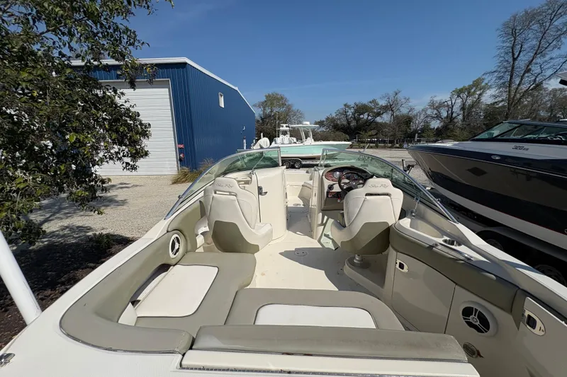 Slide: The Image of 2011 Sea Ray 185 Sport boat interior with seating and steering wheel, parked outdoors. - 20