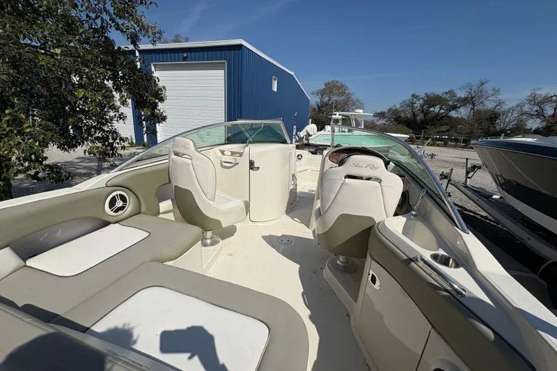 Slide: The Image of 2011 Sea Ray 185 Sport boat interior with seating and steering wheel, parked outdoors. - 21