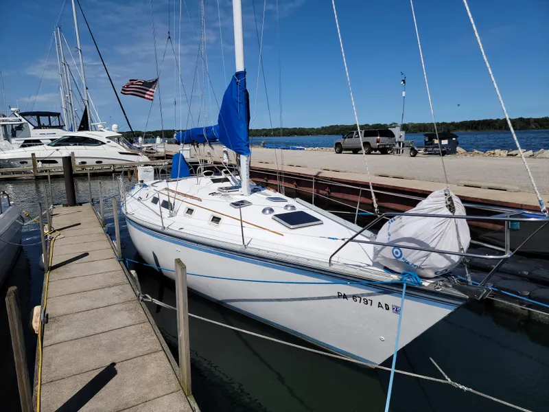 Slide: The Image of 1984 Hunter 34 sailboat docked at marina with blue sails and American flag. - 19