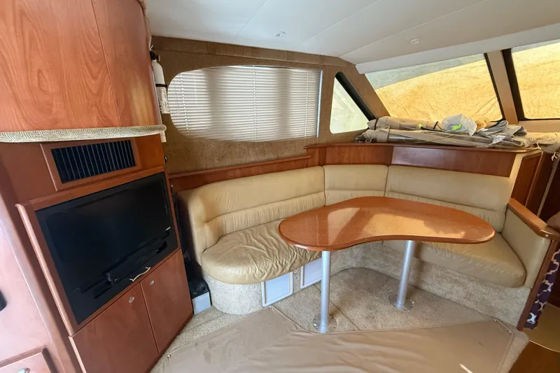 Slide: The Image of 2006 Silverton 36 Convertible yacht interior with beige seating, wooden table, and built-in TV. - 3
