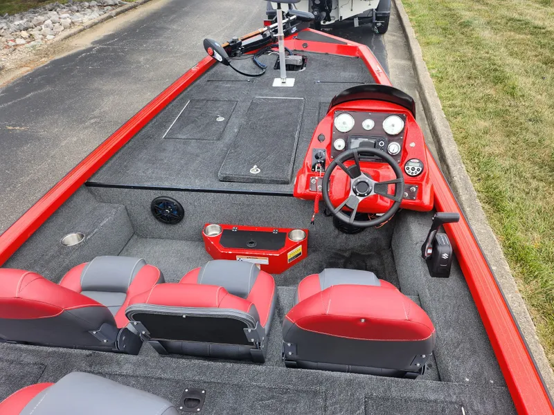 Slide: The Image of 2021 Caravelle Raptor 180 Bass boat interior with red and gray seating, steering console, and storage compartments. - 11