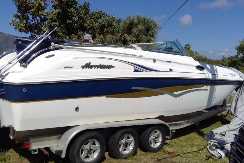 Slide: The Image of 2004 Hurricane SunDeck 260 OB boat on trailer, parked outdoors with trees in background. - 5
