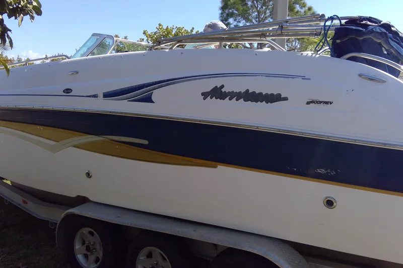 Slide: The Image of 2004 Hurricane SunDeck 260 OB boat on trailer, side view with logo and design details. - 8